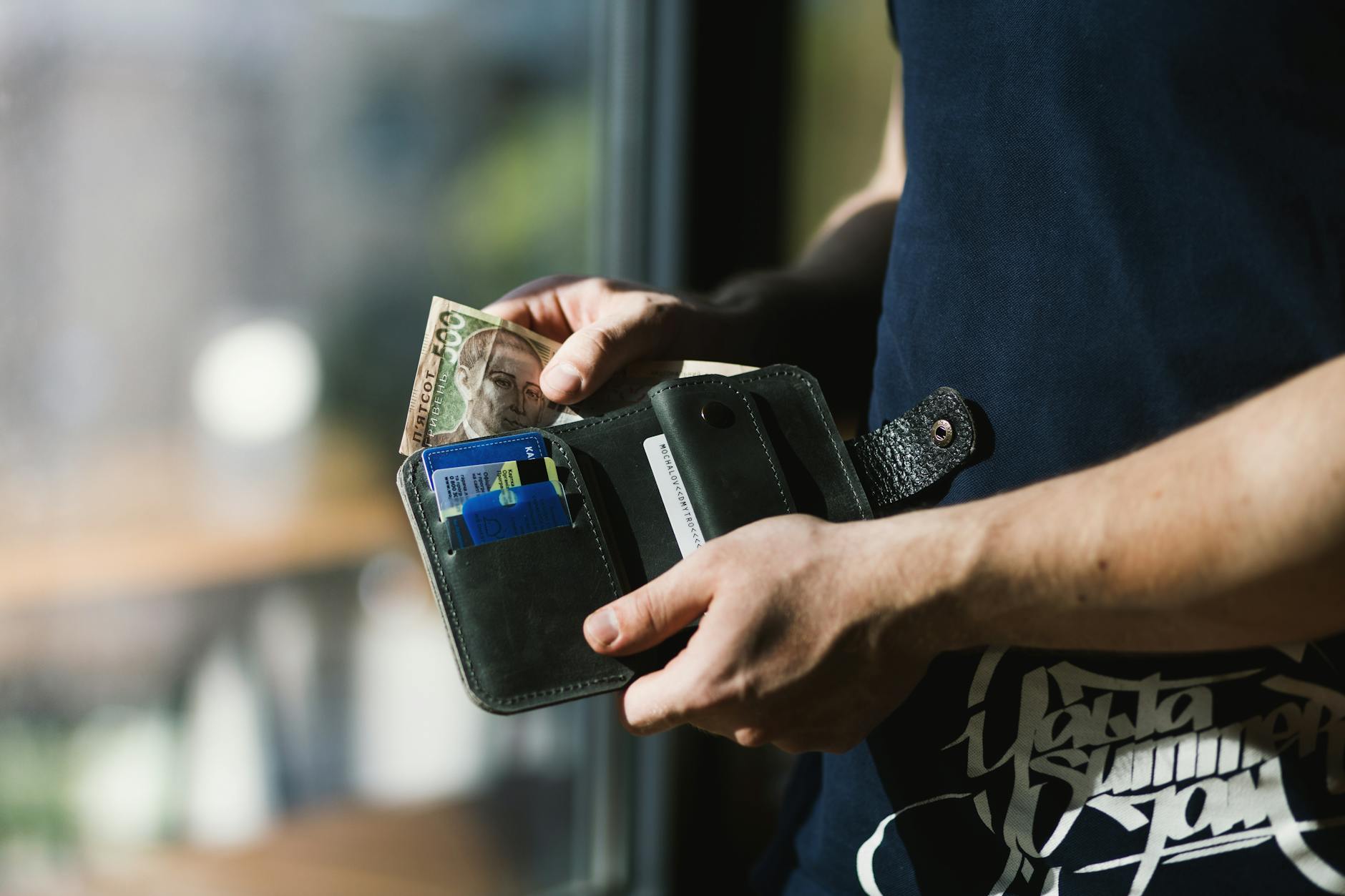 Foto Der Person, Die Schwarze Lederbrieftasche Mit Geld Hält